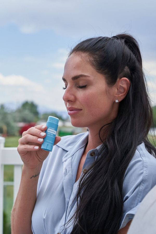 Woman holding a blue container outdoors with a blurred background