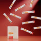 A white rectangular box labeled MegaPWT stands on a red surface, with multiple white single-serve packets floating around it against a red studio background. MetaPWR Recharge Electrolytes - Wild Strawberry