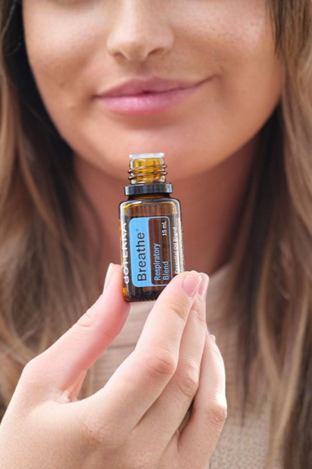 Woman holding a bottle labeled 'Breathe' close to her face
