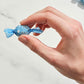 Hand holding a blue-wrapped candy against a light background