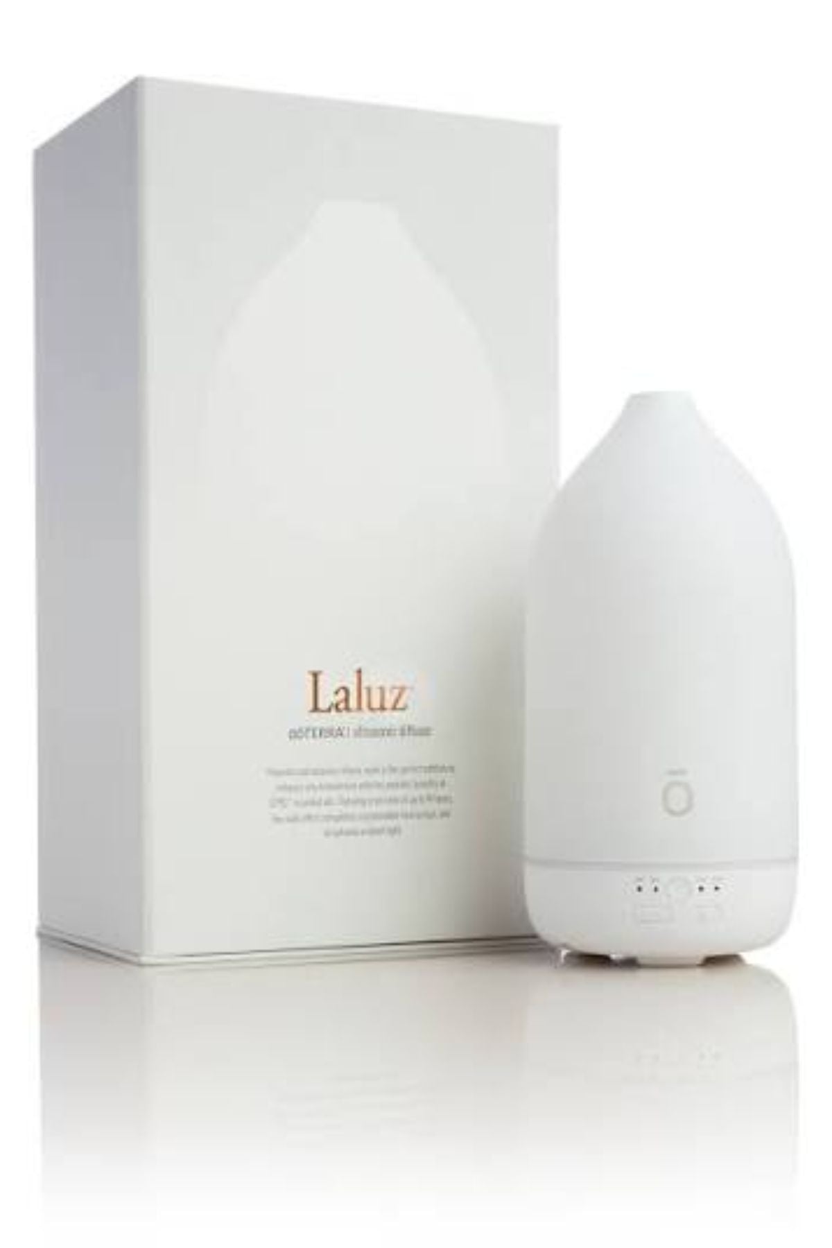 A white essential oil diffuser bottle standing next to its white packaging box, which features the brand name 'Laluz' in gold text. dōTERRA LaLuz Diffuser
