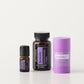 Three doTERRA Serenity products arranged on a clean white studio background: a small dark bottle, a larger amber bottle with a black cap and purple label, and a lavender deodorizer stick. doTERRA Serenity Sleep System